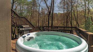 A hot tub on a wooden deck with a view of a forest.