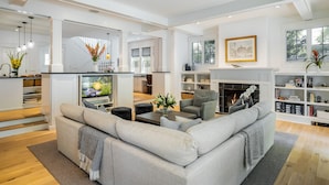 A modern living room with a grey sectional sofa, a fireplace, and a bookshelf.