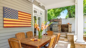 An outdoor dining area with a wooden table, chairs, and a flag.