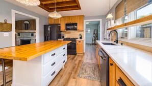 A modern kitchen with wooden cabinets, a central island, and pendant lighting.