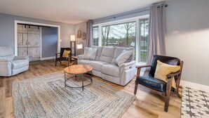 A living room with a grey sofa, a black armchair, a wooden coffee table, and a patterned rug.