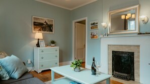 Una sala de estar con chimenea, un sofá, una mesa de centro y un cuadro en la pared.