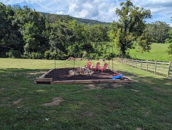 A fenced outdoor area with a raised garden bed, wooden deck, and red chairs.