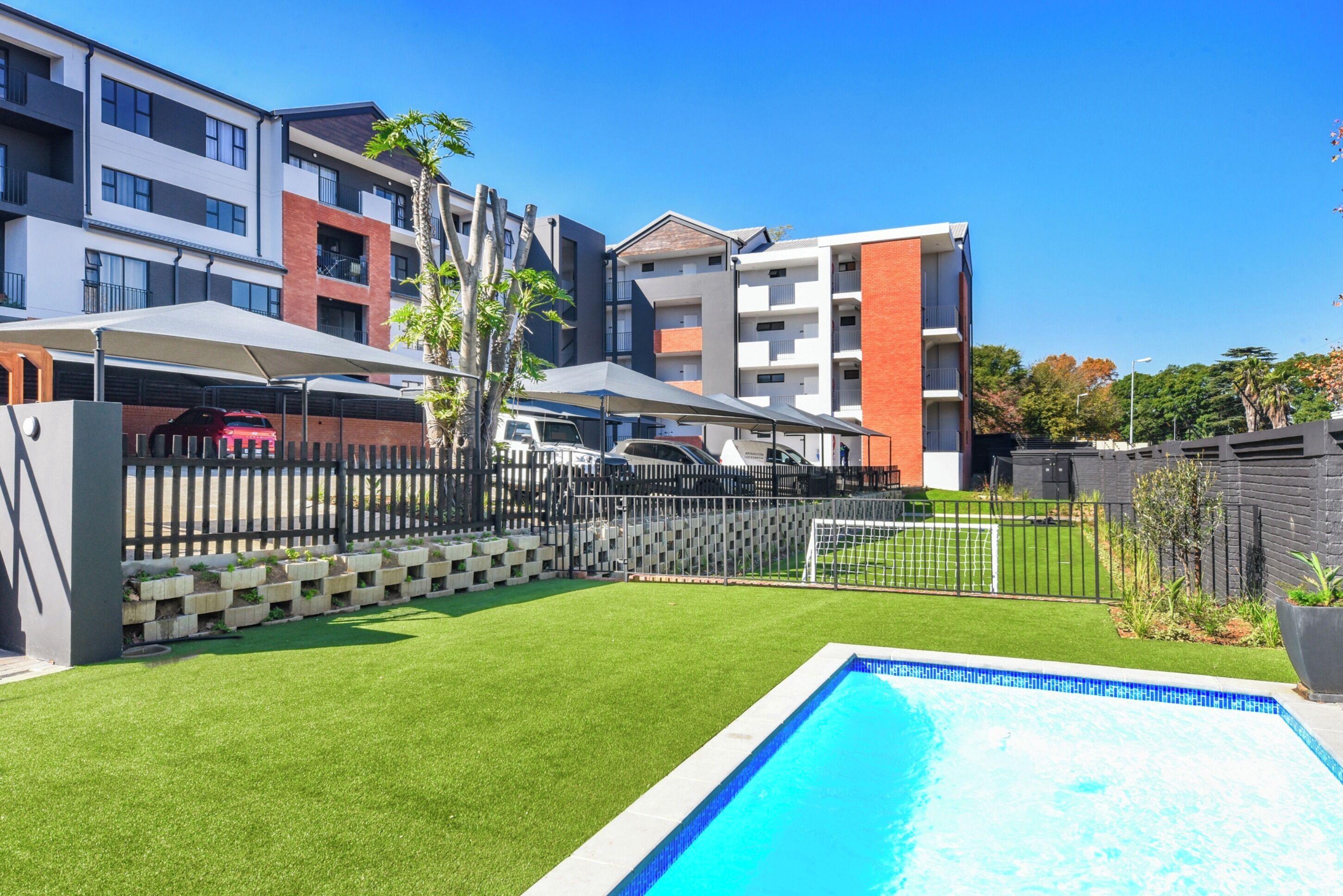 Ein Wohngebäude mit Schwimmbad, eingezäunter Garten und Sportplatz.