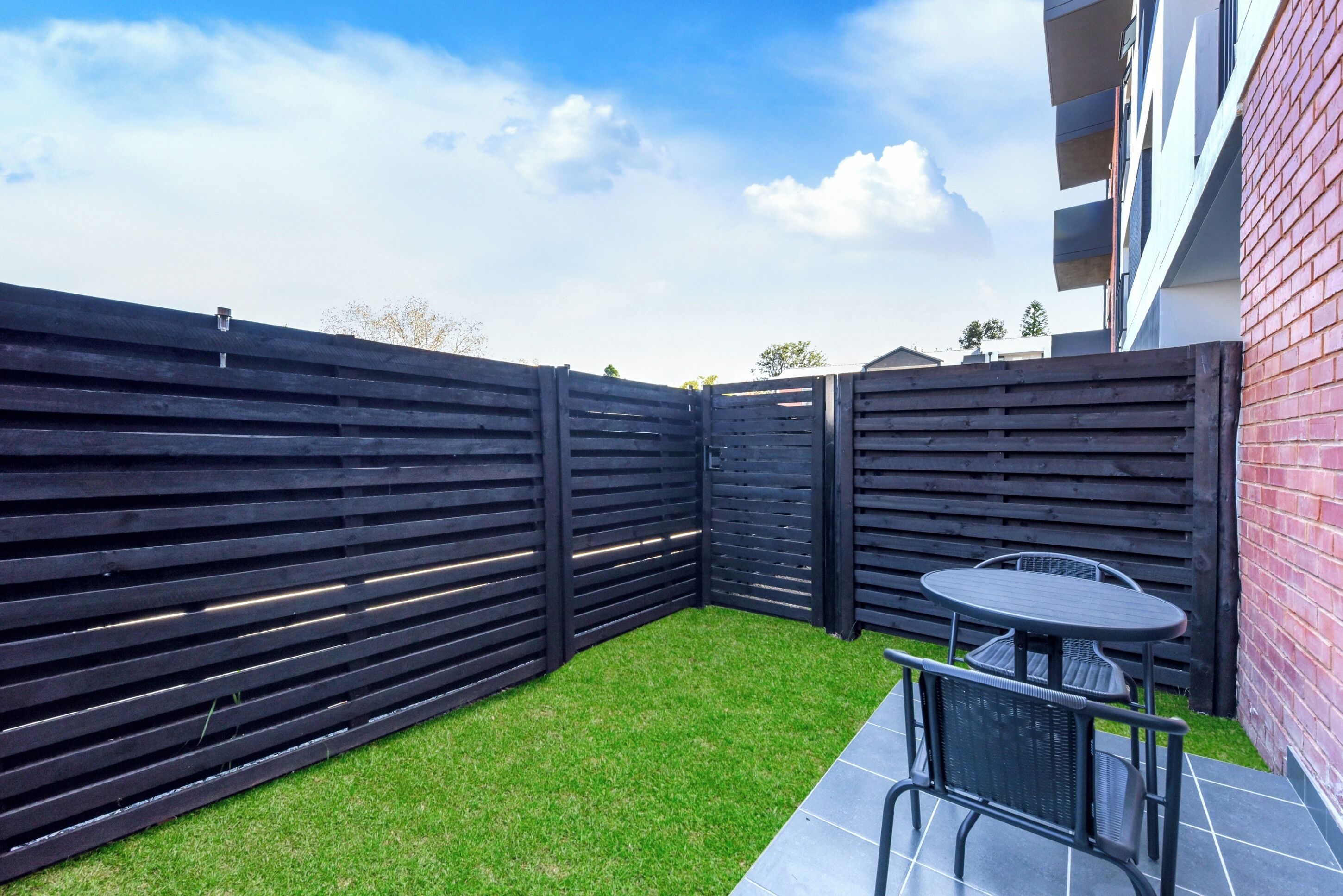 Un espacio al aire libre delimitado con pasto sintético, una mesa y sillas.
