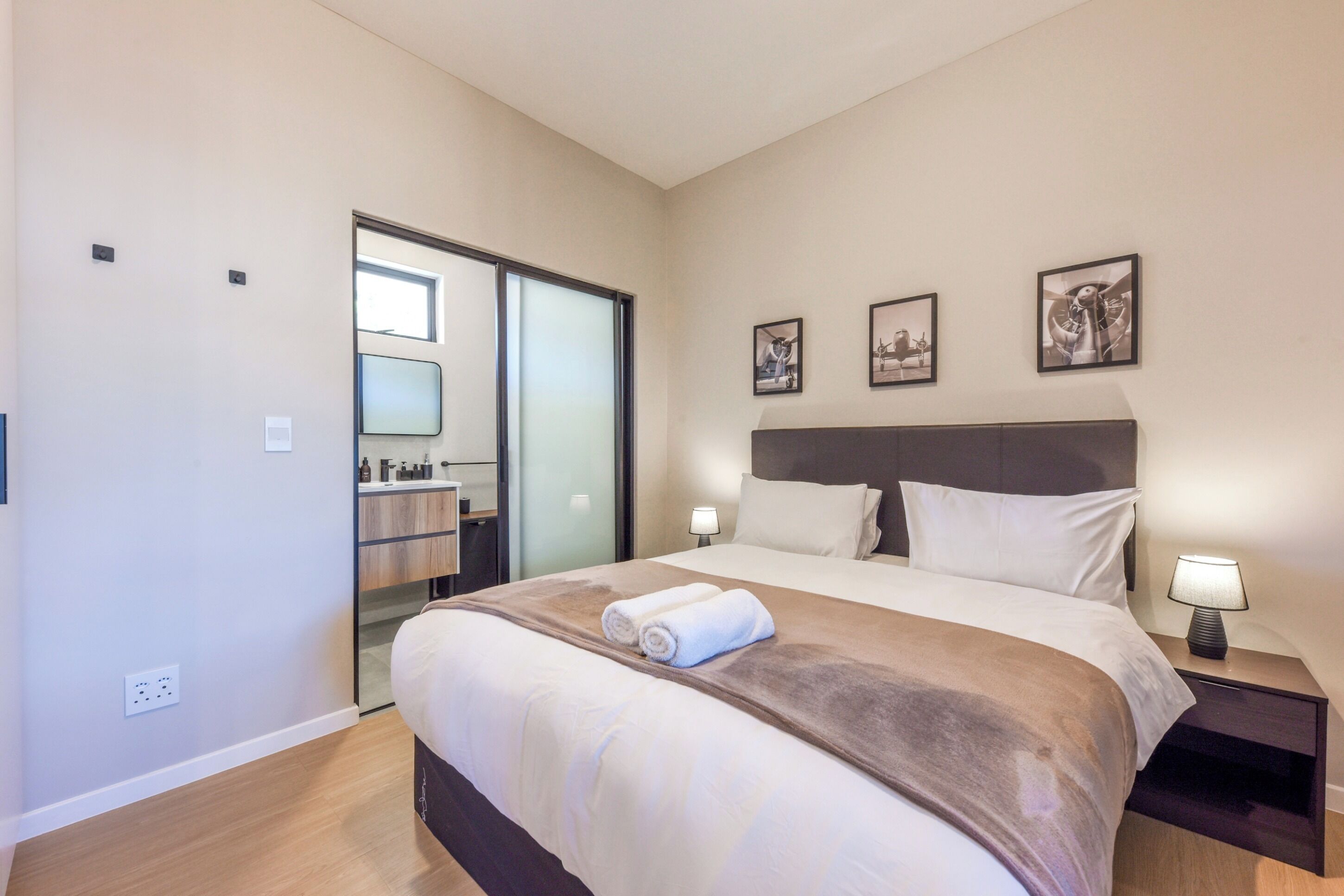 Camera d'albergo con un letto, un comodino, una lampada, uno specchio e una porta che dà su un bagno.