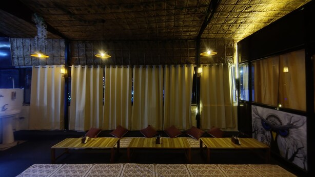 Un restaurante con una mesa larga, cortinas a rayas y luces colgantes.