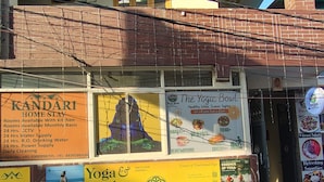 Un edificio con varios letreros que anuncian clases de yoga, un servicio de alojamiento en casas particulares y un restaurante.
