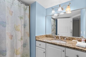 Un baño con encimera de granito, un lavabo blanco y un espejo encima.