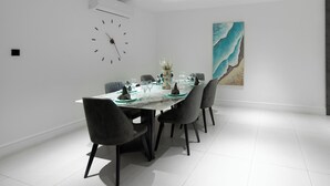Un comedor moderno con una mesa larga, seis sillas y un reloj en la pared.