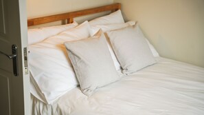 A bed with white linens and two pillows, a wooden headboard, and a door with a handle. - Crookes Gem with Garden & Alpacas Nearby (Sheffield)