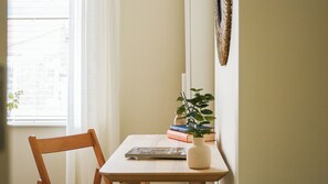 Uma cadeira e uma mesa de madeira com livros e um vaso de plantas verdes.