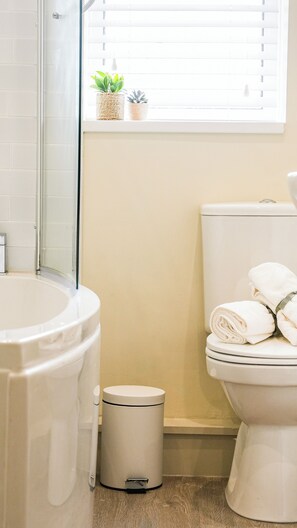A bathroom with a toilet, a trash can, and a window with plants. - Crookes Gem with Garden & Alpacas Nearby (Sheffield)