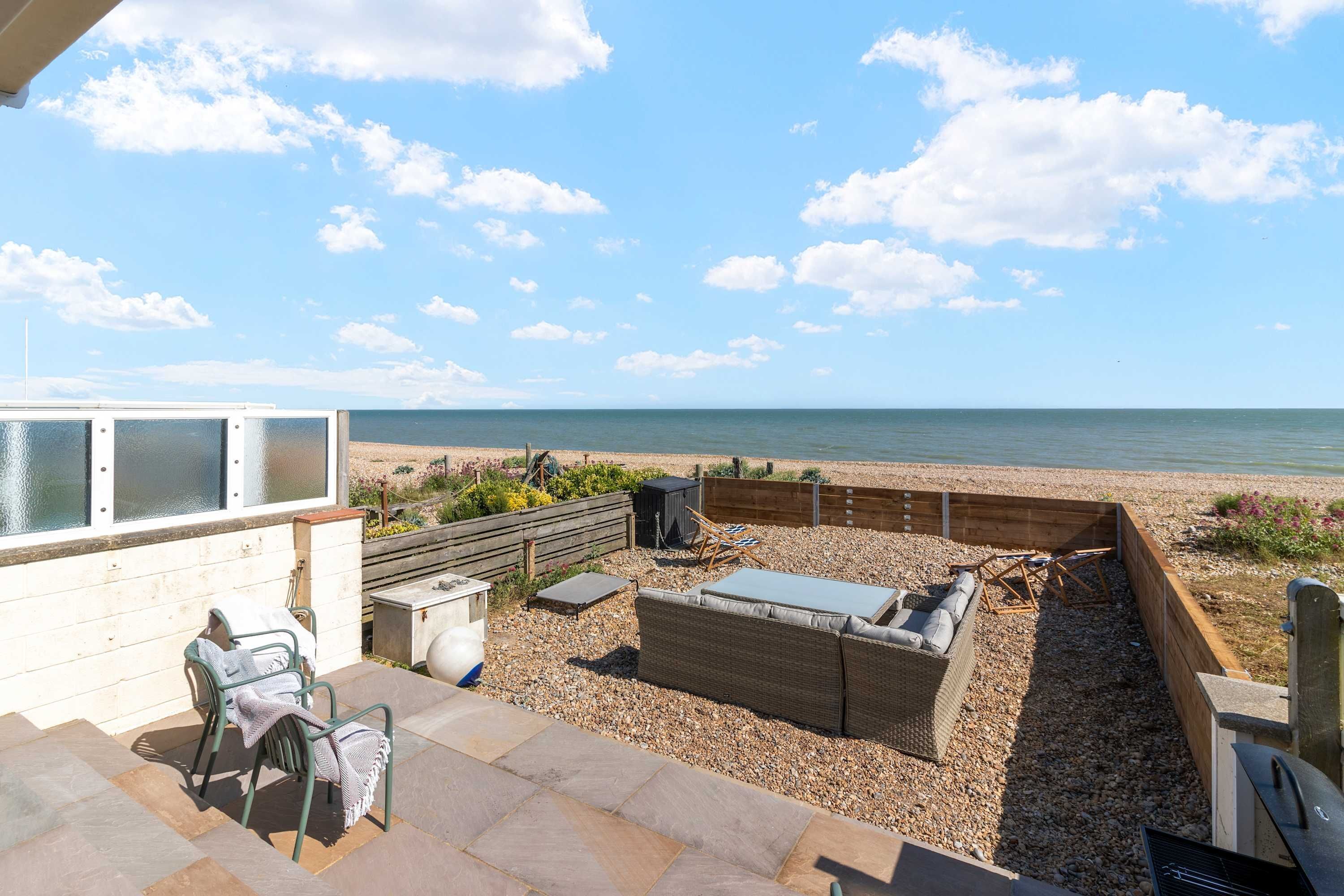 Une terrasse avec des sièges d’extérieur, un barbecue et une vue sur la plage.
