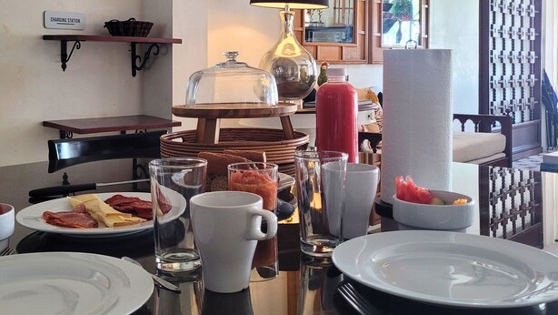 En matplats med ett bord dukat för frukost, inklusive tallrikar, glas och en kaffekanna.