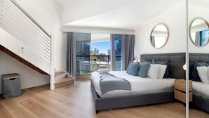 Ein modernes Schlafzimmer mit einem großen Bett, einem Balkon mit Blick auf die Stadt und einer Treppe.