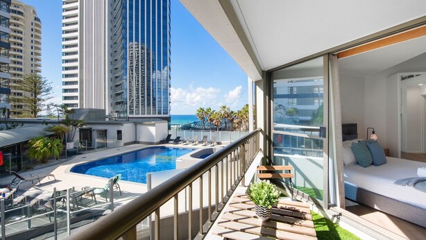 Ein modernes Apartment mit Balkon, Schwimmbad und Blick auf hohe Gebäude und den Ozean.