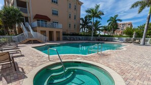 A swimming pool with a circular hot tub, surrounded by lounge chairs and a brick patio. - Bella Lago 324 by Distinctive Beach Rentals (Fort Myers Beach)