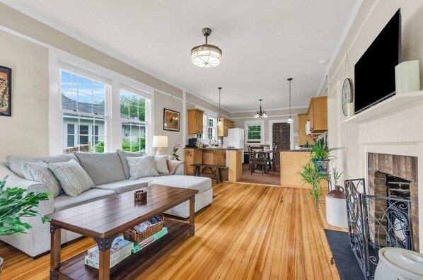 A spacious living room with a wooden floor, a sofa, a coffee table, and a fireplace.