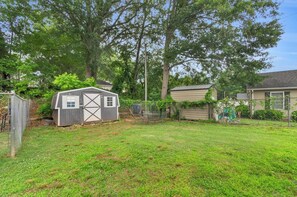 A backyard with a small shed, a fenced area, and a house.