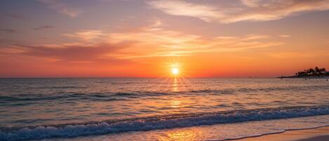 A beach with the sun setting over the ocean, creating a calm and serene atmosphere.