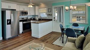 Une cuisine moderne avec des meubles blancs, des appareils en acier inoxydable et un coin repas comprenant une table et des chaises.