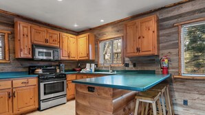 A kitchen with wooden cabinets, a stainless steel stove, a microwave, and a blue countertop. - Blue Lagoon Lakefront (Big Bear Lake)