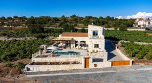A stone villa with a swimming pool, outdoor seating, and vineyard views.