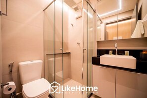 A modern bathroom with a glass-enclosed shower, a white toilet, and a black countertop with a sink.