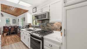 Una cocina moderna con armarios blancos, una campana extractora de acero inoxidable y techo de paneles de madera.