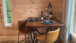 Une pièce aux murs lambrissés, avec un téléviseur diffusant une image de château, une table avec deux chaises, une bouteille et un chandelier.