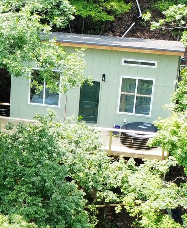 A small, single-story building with a green exterior, a front door, and a window. - Dreamy Lakeside Treehouse Hideaway/Cabin for Couples (Newport)
