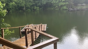 Une terrasse en bois s’étendant au-dessus d’un lac paisible, entourée d’une végétation luxuriante.