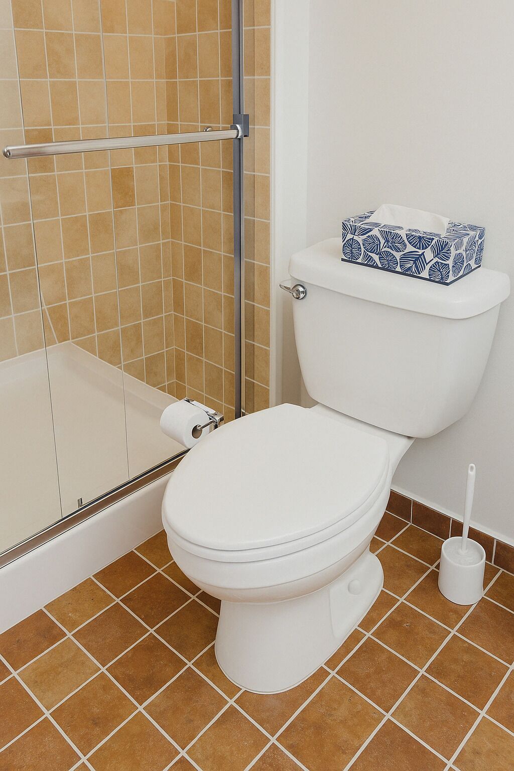 Ein Badezimmer mit Toilette, Duschbereich und Toilettenpapierhalter.