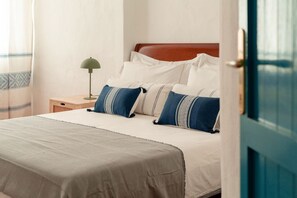 A neatly made bed with a wooden headboard, white bedding, and blue and white striped pillows. - CASA BIANCA - Charme and relax between Villasimius and Notteri (Notteri)