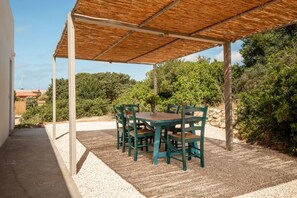 A covered outdoor area with a table and chairs, surrounded by gravel and greenery. - CASA BIANCA - Charme and relax between Villasimius and Notteri (Notteri)