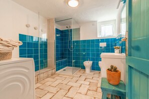 A bathroom with a glass shower enclosure, a white toilet, and a blue tiled wall. - CASA BIANCA - Charme and relax between Villasimius and Notteri (Notteri)