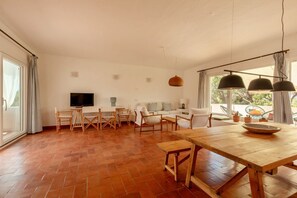 Un salón espacioso con una mesa de comedor de madera, un televisor y un sofá.