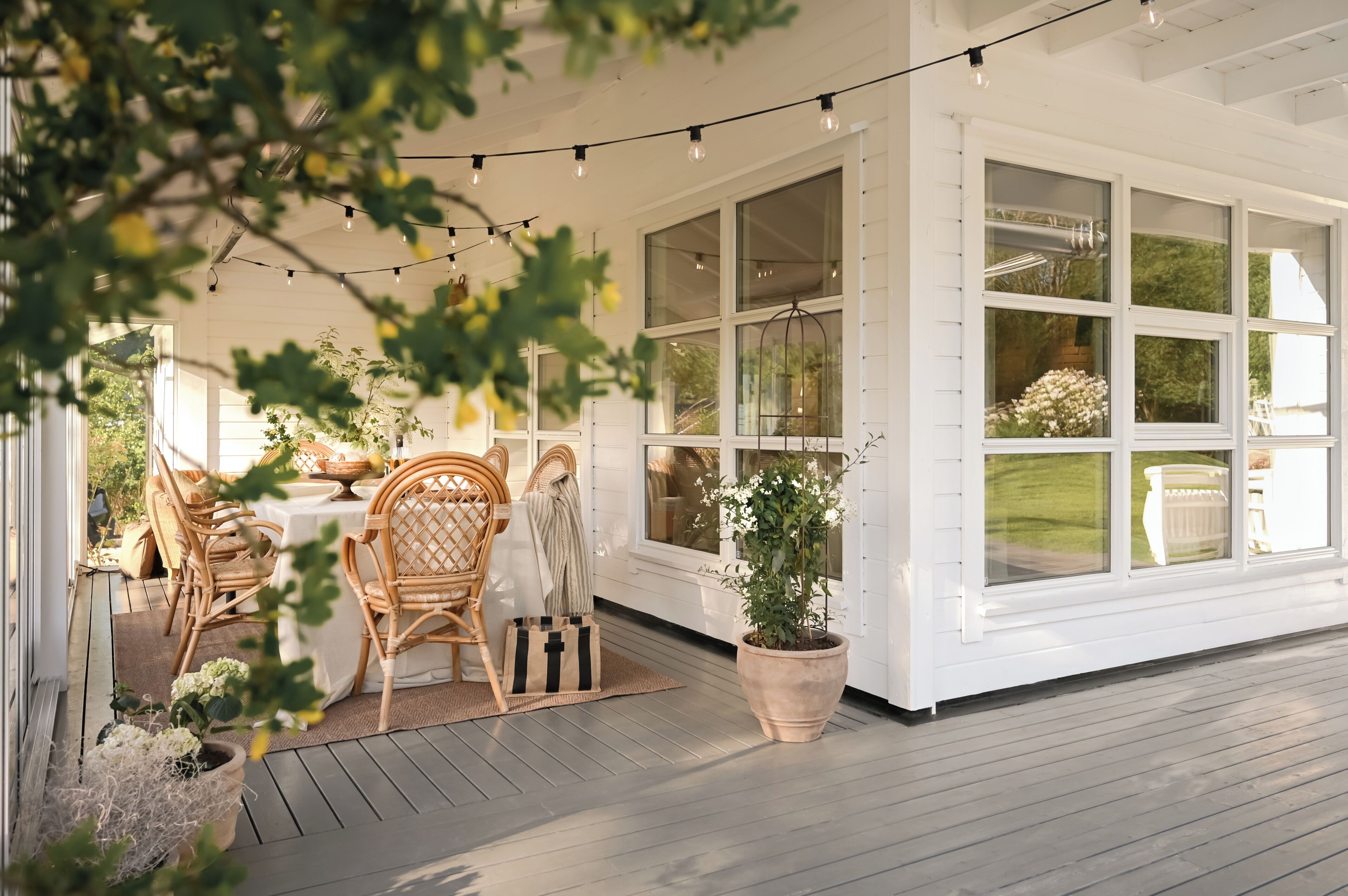 A covered patio area with a dining table, chairs, and string lights.