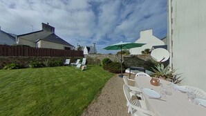 A well-maintained backyard with a lawn, a stone wall, and a dining area with outdoor furniture. - Family home - all comforts, in the heart of Roscoff (Roscoff)