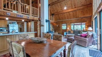A spacious wooden cabin interior with a dining area, kitchen, and living room.