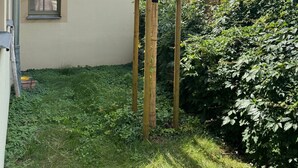 Eine Holzpergola in einem Garten, im Hintergrund ein Haus.