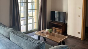 Ein Wohnzimmer mit einer Couch, einem Fernseher und einer Holzbalkendecke.