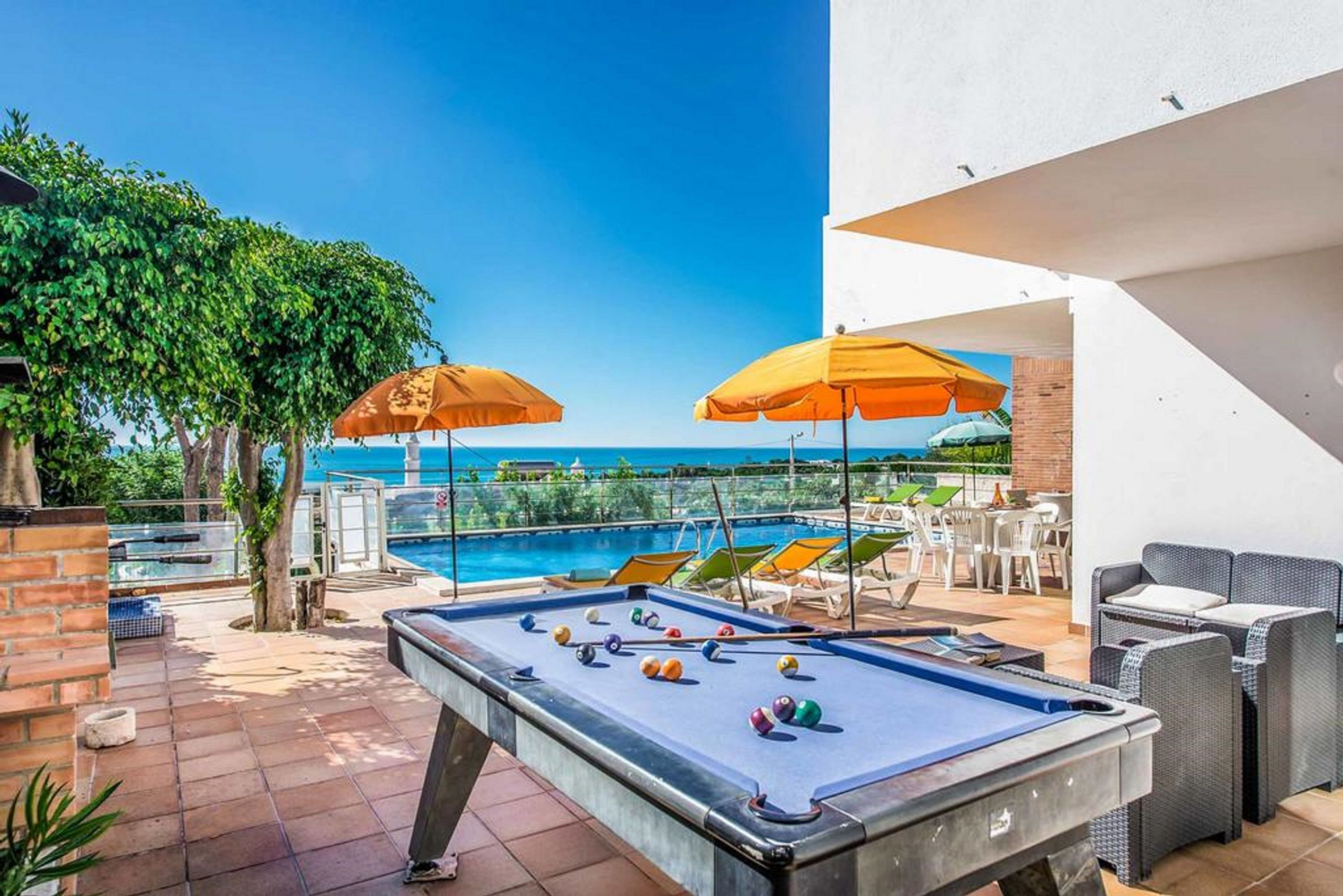 Une table de billard avec des billes, des sièges en plein air et une vue sur la mer.