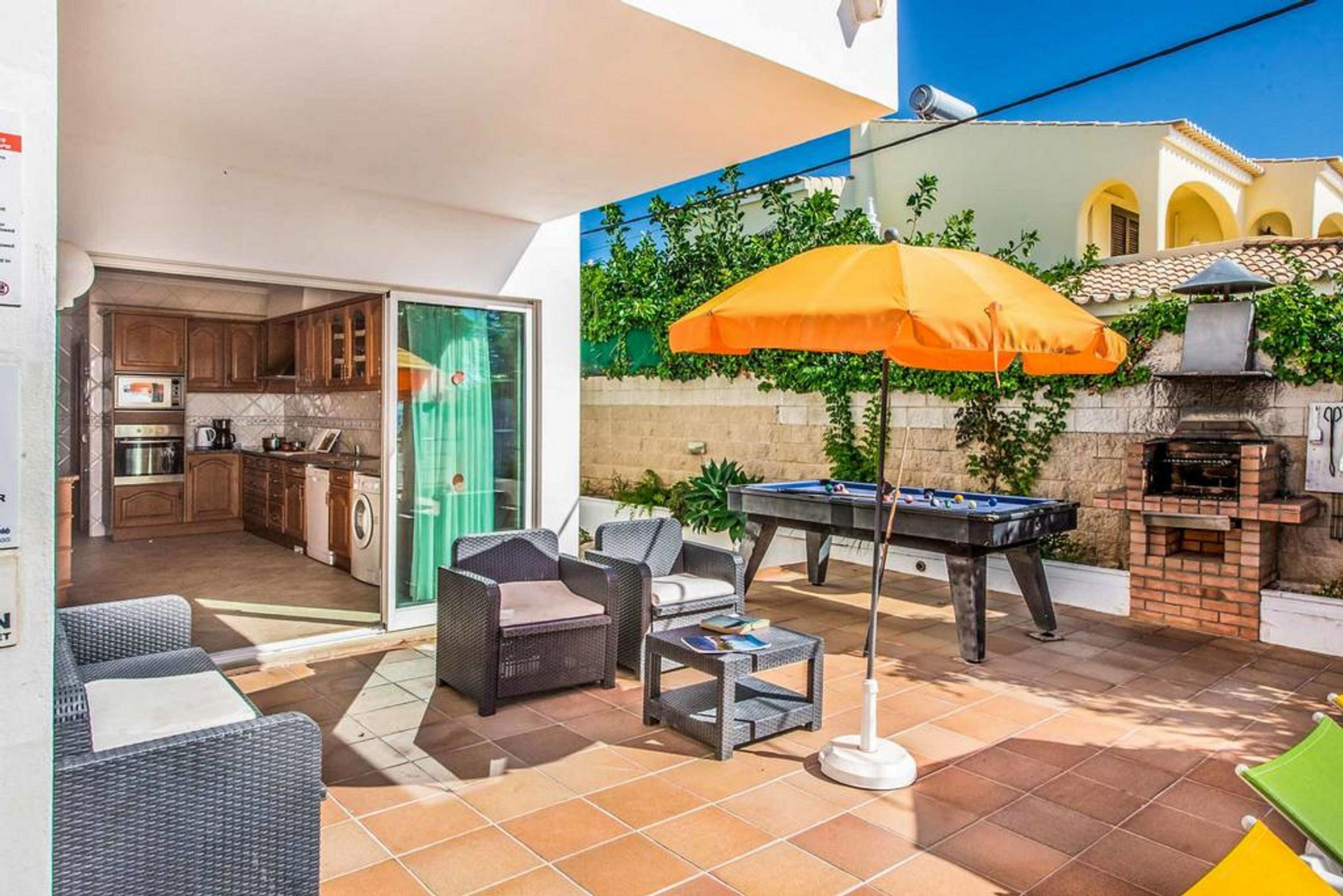 Een terras met tuinmeubilair, een pooltafel en een barbecuehoek.