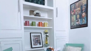 Un petit coin repas avec des chaises vertes, une table et des placards blancs au-dessus.