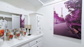 Une salle de bain avec un meuble-lavabo blanc, des vases décoratifs et une grande affiche de la Tour Eiffel.