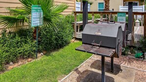 A community grill area with a grill and a sign detailing the community grill rules.