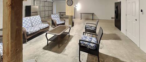A spacious living room with a ceiling fan, a dartboard, and a flat-screen TV mounted on the wall.