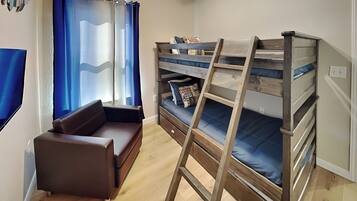 Una habitación pequeña con una cama nido, un sofá y una escalera.